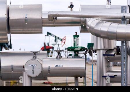 Grüne und rote Pferd pumpjack, Öl, Öl derrick Öl gut Pumpen mit dramatischen bewölkter Himmel Hintergrund Stockfoto