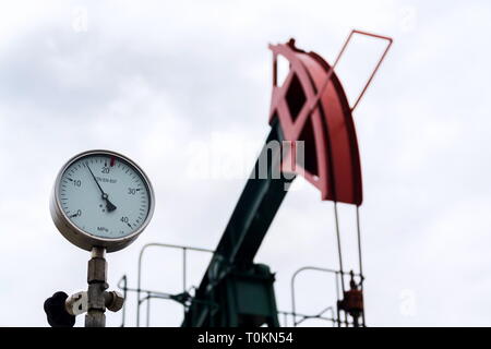 Grüne und rote Pferd pumpjack, Öl, Öl derrick Öl gut Pumpen mit dramatischen bewölkter Himmel Hintergrund Stockfoto