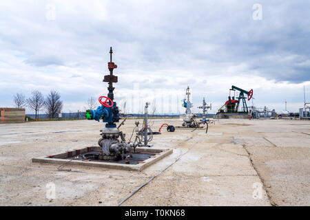 Grüne und rote Pferd pumpjack, Öl, Öl derrick Öl gut Pumpen mit dramatischen bewölkter Himmel Hintergrund Stockfoto