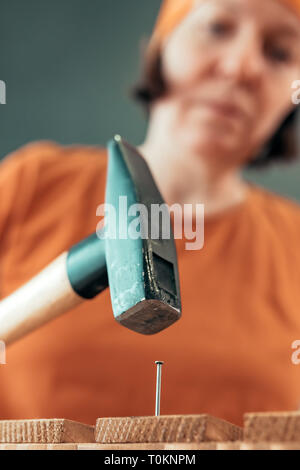 Frau Carpenter Nagel hämmern in Holzkiste in kleinen Unternehmen Holzarbeiten Workshop, selektiver Fokus Stockfoto