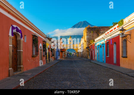 Stadtbild der Hauptstraße und gelbe Santa Catalina arch im historischen Zentrum von Antigua bei Sonnenaufgang mit dem Agua Vulkan, Guatemala. Stockfoto