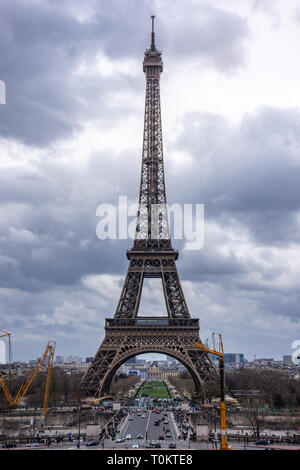 Panoramablick auf der Straße vor dem Eiffelturm, Autos und Touristen auf der Durchreise gegen einen bewölkten Himmel. Paris, Frankreich Stockfoto