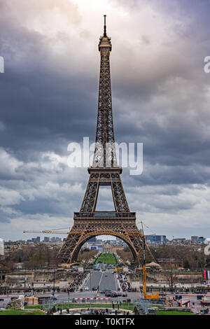 Panoramablick auf der Straße vor dem Eiffelturm, Autos und Touristen auf der Durchreise gegen einen bewölkten Himmel. Paris, Frankreich Stockfoto