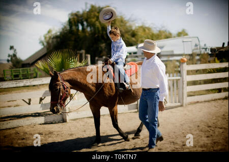 Junge Pferd reitet als Vater Uhren Stockfoto