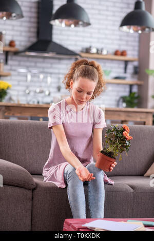 Miserable ginger junge Dame auf grau Couch mit Pot. Stockfoto
