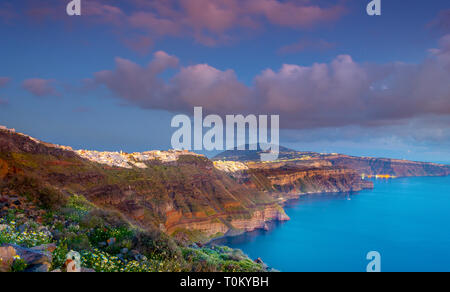 Blick am Abend von Fira, Caldera, Vulkan von Santorini, Griechenland mit Kreuzfahrtschiffen bei Sonnenuntergang. Dramatischer Wolkenhimmel. Stockfoto