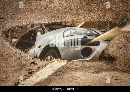 Reflexion der verbrannten Auto in der Pfütze auf Asphalt Stockfoto