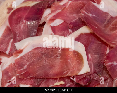 Leckere Scheiben Prosciutto auf Holztafel, Ansicht von oben Stockfoto