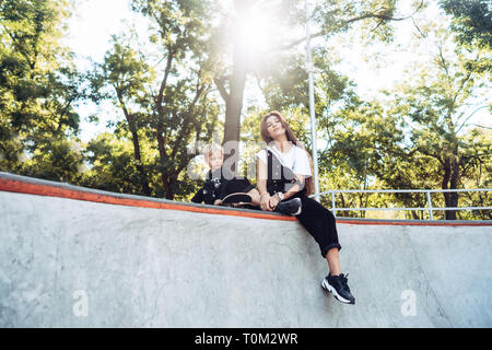 Schöne junge Hipster Mamma und kleinen Sohn Am Skatepark Stockfoto