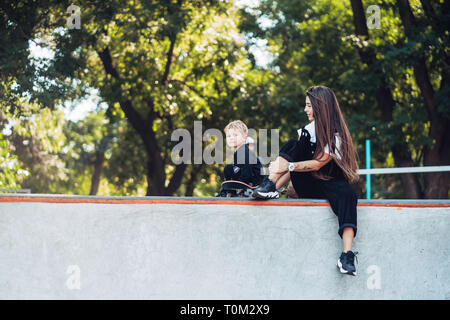 Schöne junge Hipster Mamma und kleinen Sohn Am Skatepark Stockfoto