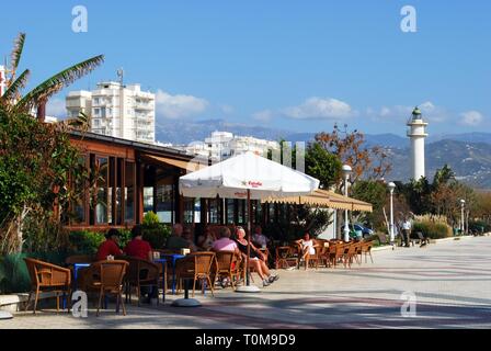 Touristen und Cafés entlang der Promenade mit den Leuchtturm auf der Rückseite, Torre del Mar, Provinz Malaga, Andalusien, Spanien, Europa. Stockfoto