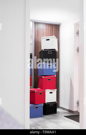 Gestapelte Kisten in verschiedenen Farben in einem hellen Raum in einem Türrahmen Stockfoto