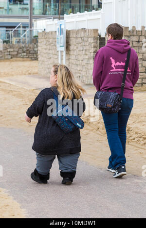 Zwei Frauen, eine von Kleinwuchs, Wandern entlang der Promenade an der Durley Chine, West Underfcliff Promenade, Bournemouth, Dorset UK im März Stockfoto