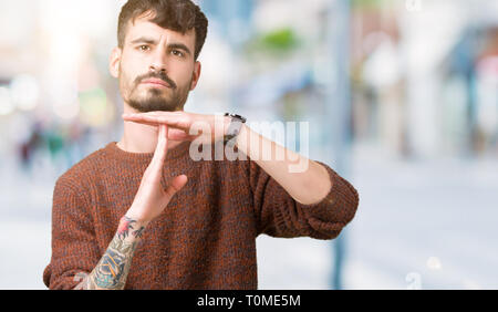Jungen gutaussehenden Mann tragen winter Pullover über isolierte Hintergrund tun time out Geste mit den Händen, frustriert und ernstes Gesicht Stockfoto