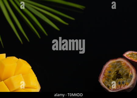 Eine geschälte Ananas, Bambus und Passionsfrucht. Frische tropische Früchte. Auf einem schwarzen Hintergrund. Ansicht von oben. Kopieren Sie Platz. Stockfoto