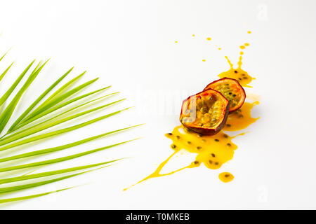 Passionsfrucht splasing und Bambus Blatt. in Stücke oder Scheiben geschnitten, Passionsfrucht. Schmiert oder Blot der Leidenschaft Fruchtsaft auf weißem Hintergrund. Exotische Früchte Stockfoto