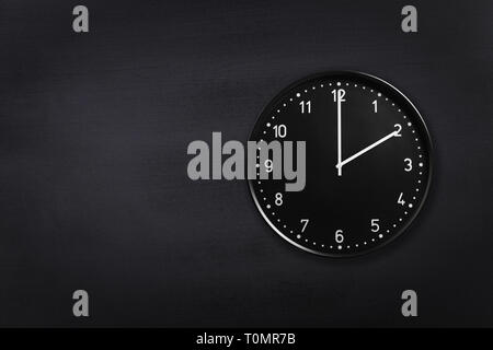 Wanduhr mit 2 o'clock auf Schwarze Schiefertafel Hintergrund. Büro Uhr zeigt 2:00 oder 2:00 Uhr am Schwarzen Textur Stockfoto