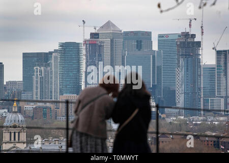 Besucher in Greenwich Park, South London, schauen Sie sich die Aussicht auf die Themse in Richtung Canary Wharf. Stockfoto