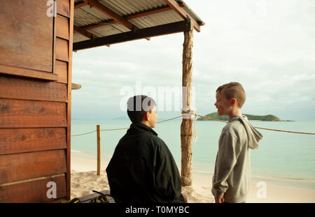 9 Jahr alt und 7 Jahre alten Jungen außerhalb eines Lean Beach Hut auf Putney Strand, Great Keppel Island, Queensland, Australien Stockfoto