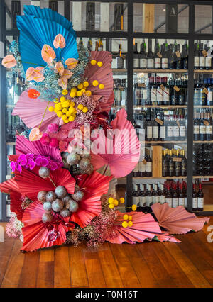 Großes Blumenarrangement auf hölzernen jarrah Dielen vor Rotwein Flaschen in Thomsons Restaurant die Insel Rottnest Island WA Australien. Stockfoto
