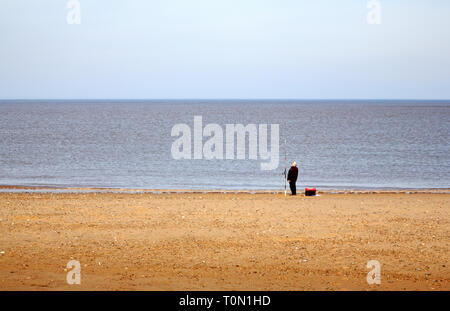 Ein einsamer See Angler auf einem North Norfolk Strand in Bacton-on-Sea, Norfolk, England, Vereinigtes Königreich, Europa. Stockfoto