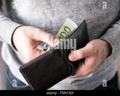 Hände nehmen Sie Euro aus dem Geldbeutel. Nahaufnahme auf die Hände eines Menschen, wie er ist, eine Banknote aus seiner Brieftasche Stockfoto