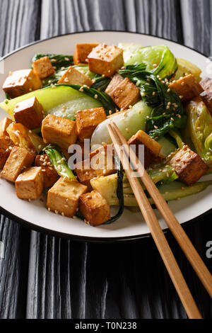 Pfannengerichte Tofu mit Bok Choy und Sesam close-up auf einem Teller auf den Tisch. Vertikale Stockfoto