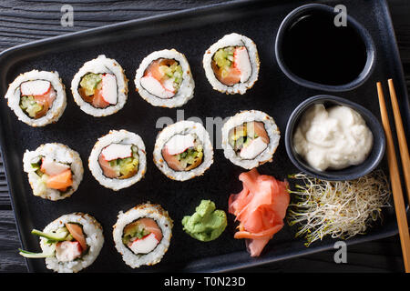 Einstellen der japanischen Rollen uramaki serviert mit Saucen, Ingwer und Wasabi closeup auf einem Teller auf den Tisch. horizontal oben Ansicht von oben Stockfoto