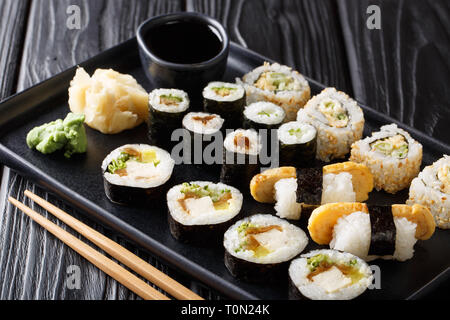 Köstliche japanische Sushi Rollen große mit Meeresfrüchten, Gemüse, Tofu und tamago Closeup auf einem Teller auf dem Tisch. Horizontale Stockfoto