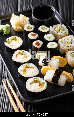 Große Auswahl an japanischen Rollen wie Hosomaki, Uramaki, Maki, Nigiri, Tamagoyaki serviert mit Ingwer, Wasabi und Sojasauce close-up auf einem Schild auf dem Ta Stockfoto