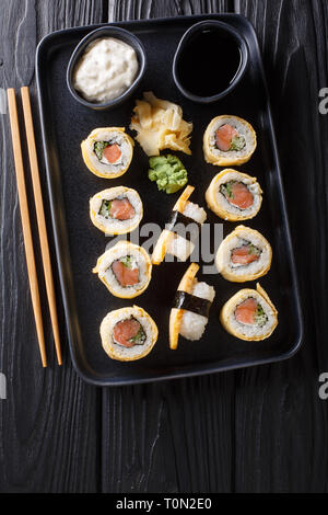 Tamagoyaki Sushi Roll mit Reis, Käse, Lachs und Avocado closeup auf einem Teller auf den Tisch. Senkrechte Draufsicht von oben Stockfoto