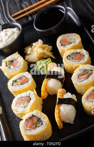 Tamagoyaki Sushi Roll mit Reis, Käse, Lachs und Avocado closeup auf einem Teller auf den Tisch. Vertikale Stockfoto