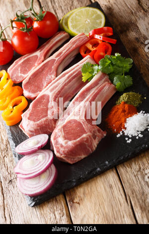 Ungekocht Lammkoteletts mit frischem Gemüse Zutaten und Gewürze close-up auf dem Tisch. Vertikale Stockfoto