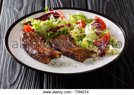 Frisch Lammkoteletts mit frischem Gemüse Salat close-up auf einem Teller auf den Tisch. Horizontale Stockfoto