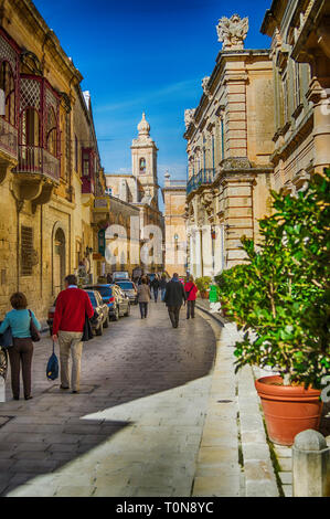 Valletta, Malta - 18. Februar 2013 mittelalterliche Altstadt typische Gasse mit Autos und Menschen. Bunte Rot, Gelb, Blau, Grün Balkone und Türen Stockfoto