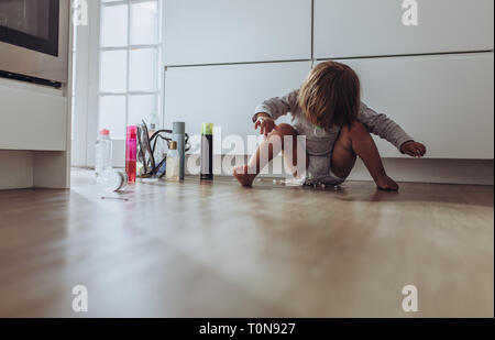 Kid spielen zu Hause mit Haushaltswaren. Kid spielen allein zu Hause sitzen auf dem Boden. Stockfoto