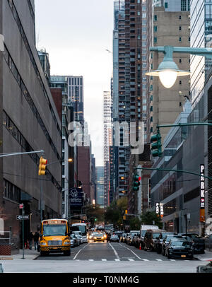 New York City, Vereinigte Staaten - 17. November 2018: Autos, Taxis und eine Schule mit dem Bus entlang der langen geraden Straße zwischen den Wolkenkratzern der West 42th stre Stockfoto