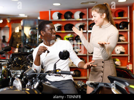 Gerne fröhliche positive lächelnde Paar mit Wahl in modernes Motorrad salon zufrieden Stockfoto