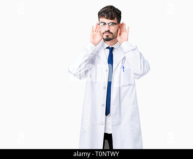 Junge Wissenschaftler Mann mit weißer Mantel über isolierte Hintergrund versuchen, beide Hände am Ohr Geste zu hören, neugierig, für Klatsch und Tratsch. Anhörung pro Stockfoto