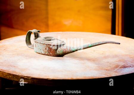 Alten rostigen Oilcan am runden Tisch. Lange Nase, schmutzigen Körper - Begriff Stockfoto