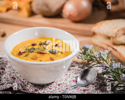Weiche, cremige Kürbissuppe in einer Schüssel auf Holz Hintergrund. gesunde Gemüse püriert mit Kräutern und Samen auf der Oberfläche Stockfoto