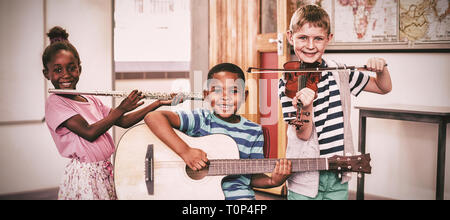 Portrait von spielenden Kindern Musikinstrumente in Klassenzimmer Stockfoto