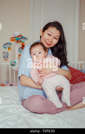 Porträt der schönen gemischten Rennen asiatischen Mutter Holding berühren, umarmen Sie cute adorable neugeborenes Baby. Frühe Entwicklung und Gesundheit leben Stockfoto