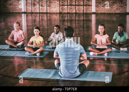 Schülerinnen und Schüler und Lehrer meditieren während Yoga-Kurs Stockfoto