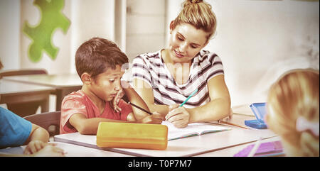 Lehrer, die Hilfe für Kinder bei den Hausaufgaben im Klassenzimmer Stockfoto