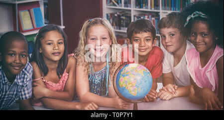 Lachende Kinder mit Globus auf Tisch Stockfoto