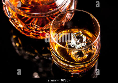 Whiskey Glas halten von Menschen Hand und Kristall Karaffe auf dunklem Hintergrund. Selektive konzentrieren. Kopieren Sie Platz. Stockfoto