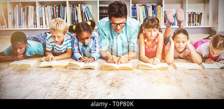 Lehrer und Kinder lesen Buch in Bibliothek Stockfoto