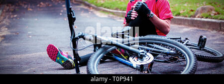 Männliche Radfahrer verletzt beim fallen vom Mountainbike Stockfoto