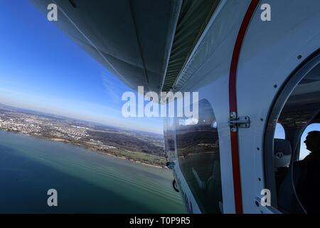 Friedrichshafen, Deutschland. 21 Mär, 2019. Der Zeppelin NT (Neue Technologie) fliegt über den Bodensee zu Beginn der Saison, während Friedrichshafen im Hintergrund gesehen werden kann. Credit: Felix Kästle/dpa/Alamy leben Nachrichten Stockfoto